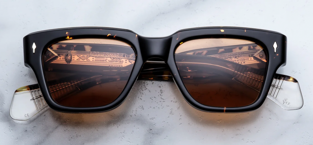A front-facing product shot of Jacques Marie Mage Fellini sunglasses in the Tokyo colourway. The medium-to-wide-fit rectangular frame features soft, sculptural angles crafted from a 10mm thick polished Havana tortoiseshell cellulose acetate. Vibrant, solid orange 4-base lenses are nestled within the frame, flanked by signature sterling silver arrowhead pins positioned horizontally on the upper corners