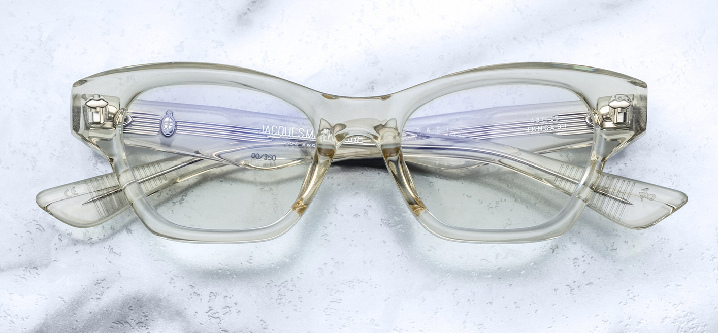 Jacques Marie Mage Grace 2 sunglasses in Sunkiss, featuring a petite cat-eye silhouette with a subtle lift in the eye area. The frame is crafted from 10mm translucent yellow cellulose acetate, accented with silver double arrowhead front pins and exposed silver wirecore details. The clear CR39 lenses offer a classic optical look