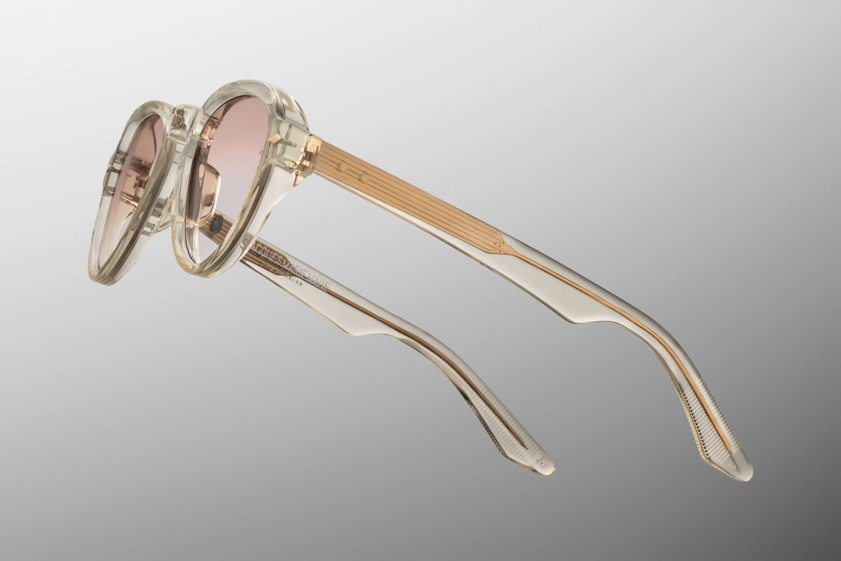 Side profile view of the Jacques Marie Mage Hatfield from the Photochromic Collection in Halo. The focus is on the thick, custom double-laminated temple arms crafted from Polished Brut beige acetate. A premium, custom Light Gold 5-barrel hinge seamlessly attaches the side arms to the translucent front frame face. Available at WINK Optometrists.
