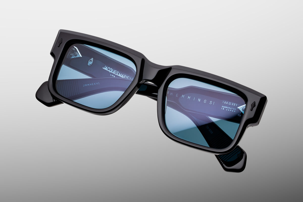 Extreme close-up of the front corner of Jacques Marie Mage Hemmings Mystique sunglasses. The shot highlights the premium, highly polished 10mm thick acetate, deep structural beveling around the lens rim, and the iconic, flush-mounted sterling silver arrowhead pin.