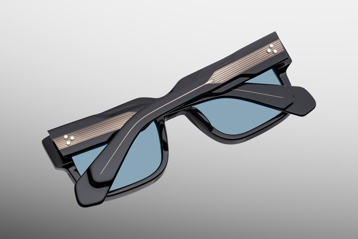 Close-up view of the inner back frame of Jacques Marie Mage Hemmings Mystique sunglasses. It shows the heavy-duty, gold-foiled engraved text displaying the model name and limited-edition batch number, alongside the robust custom tension-secured 7-barrel hinge.
