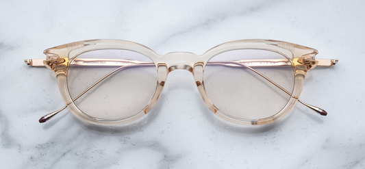 Front view of JMM Hisao in Pearl: oval full‑rim frame in translucent pearl acetate, pale warm tones, clear lenses. Subtle keyhole bridge, thin titanium temples just visible behind rims