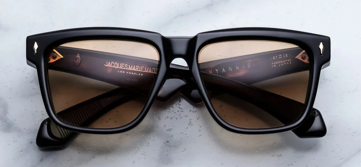 Front view of Jacques Marie Mage Hyannis sunglasses in Noir 15, showing the bold black rectangular acetate frame and signature 18k gold arrowhead pins.