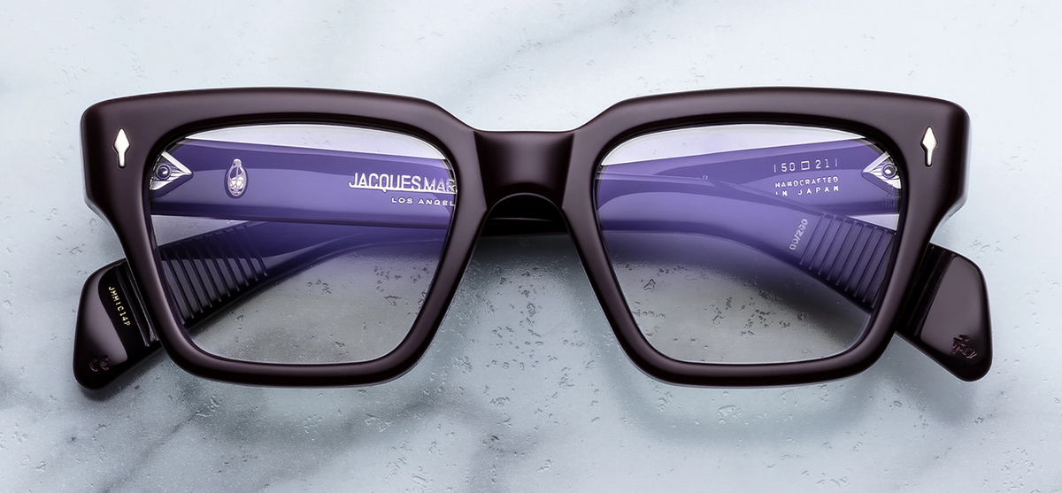 Front view of Jacques Marie Mage Ichikawa RX eyeglasses in Wine. The frame features a bold, structured, mid-century modern trapeze silhouette with strong geometric angles. The 10mm thick cured cellulose acetate reveals a deep, rich translucent burgundy-red wine tone. Signature sterling silver arrowhead front pins decorate the upper outer corners of the frame face. Available at WINK Optometrists