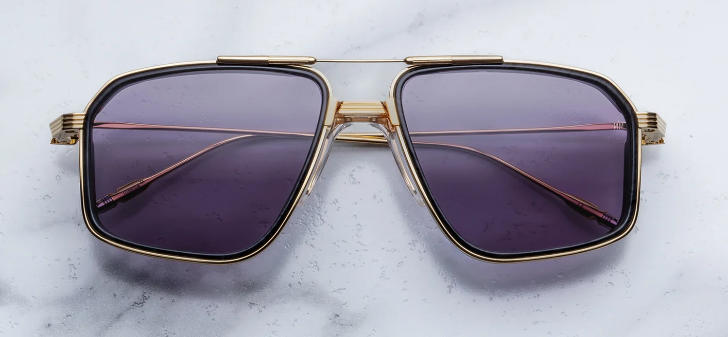 Front view of Jacques Marie Mage Jagger sunglasses in Ebony, showing oversized 1970s-style titanium aviator frames in Moon Gold with black burlwood acetate inner rim inserts and Nimbus gray lenses