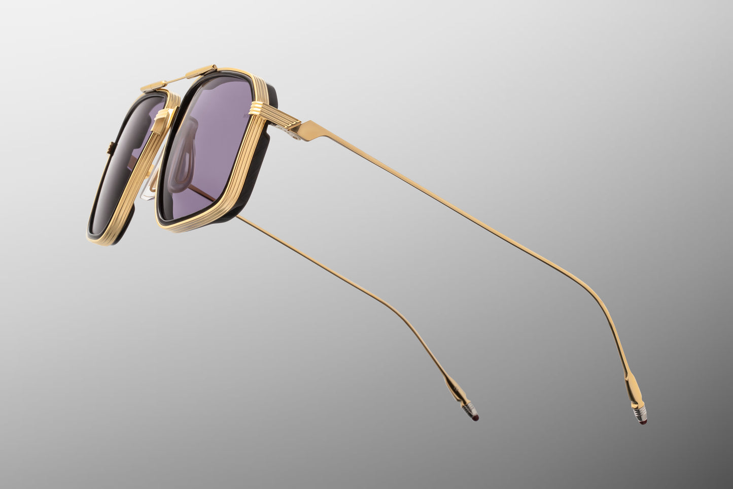 Side view of the JMM Jagger Ebony sunglasses temple arm, showcasing the sleek, polished Moon Gold titanium temples, custom monoblock hinges, and clean metallic wire architecture