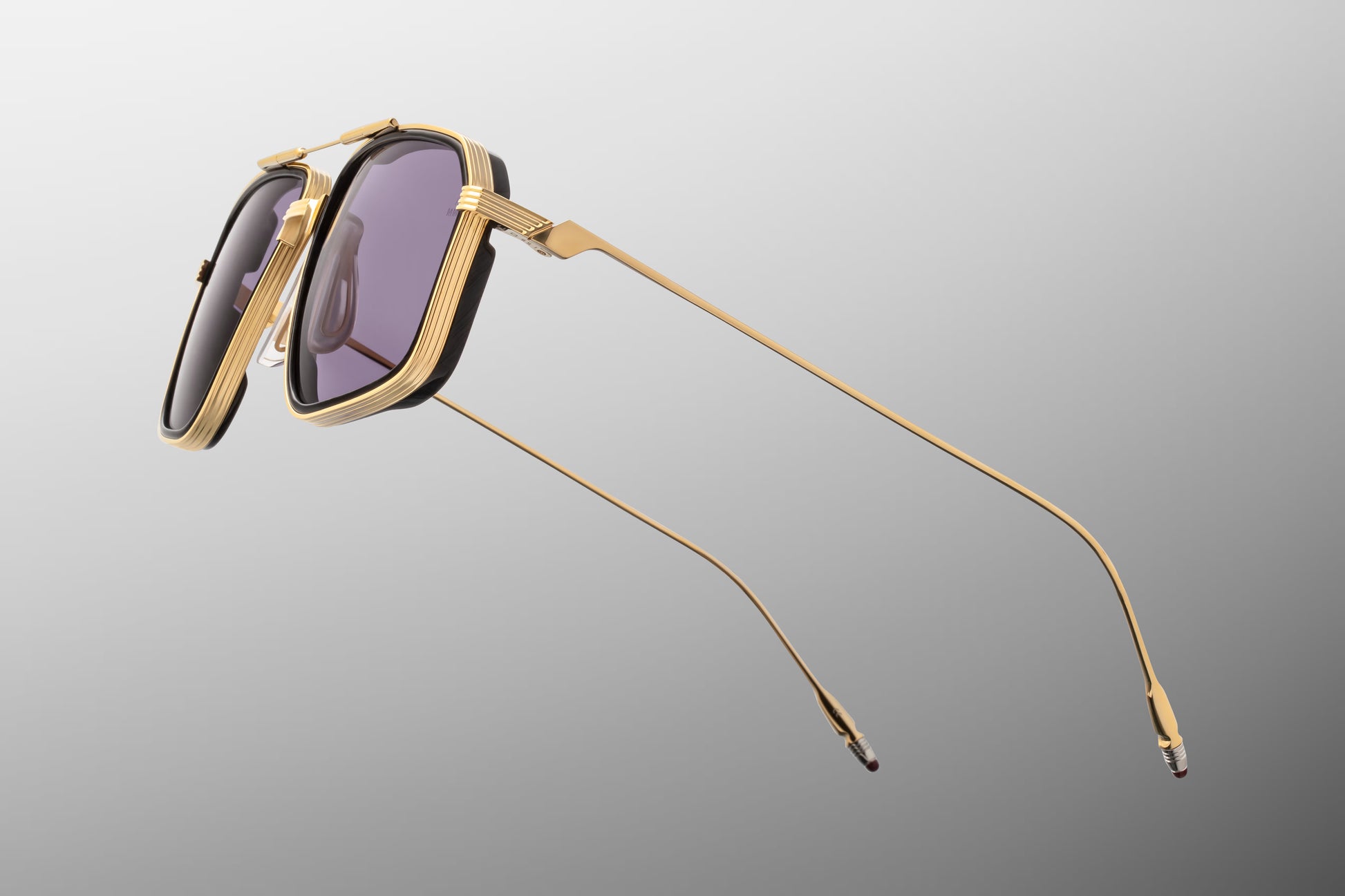 Side view of the JMM Jagger Ebony sunglasses temple arm, showcasing the sleek, polished Moon Gold titanium temples, custom monoblock hinges, and clean metallic wire architecture
