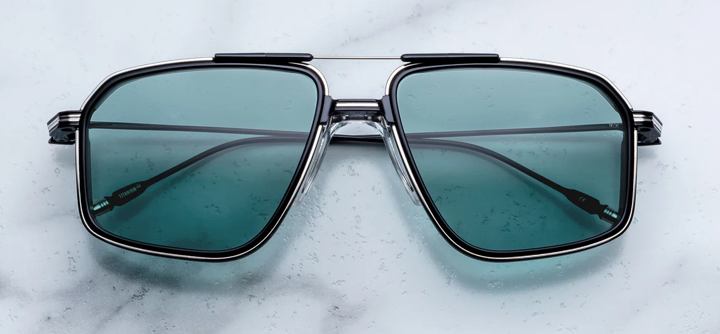 Front view of Jacques Marie Mage Jagger sunglasses in Paon, featuring an oversized 1970s-style beta titanium aviator frame in polished black with striking turquoise blue lenses