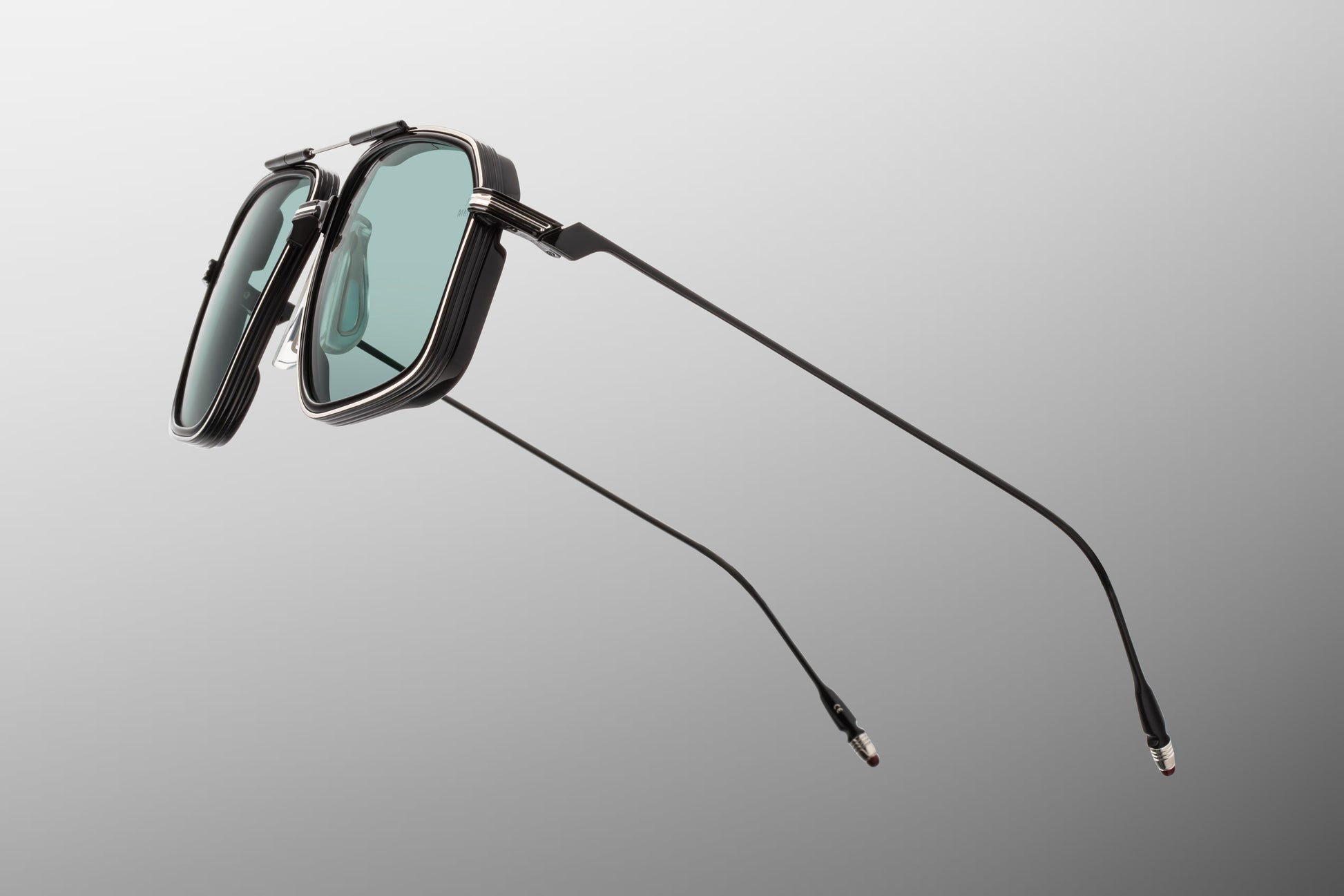 Side view of the JMM Jagger Paon sunglasses temple arm, highlighting the ultra-slim, glossy polished black titanium temples and their seamless transition into the monoblock hinges.