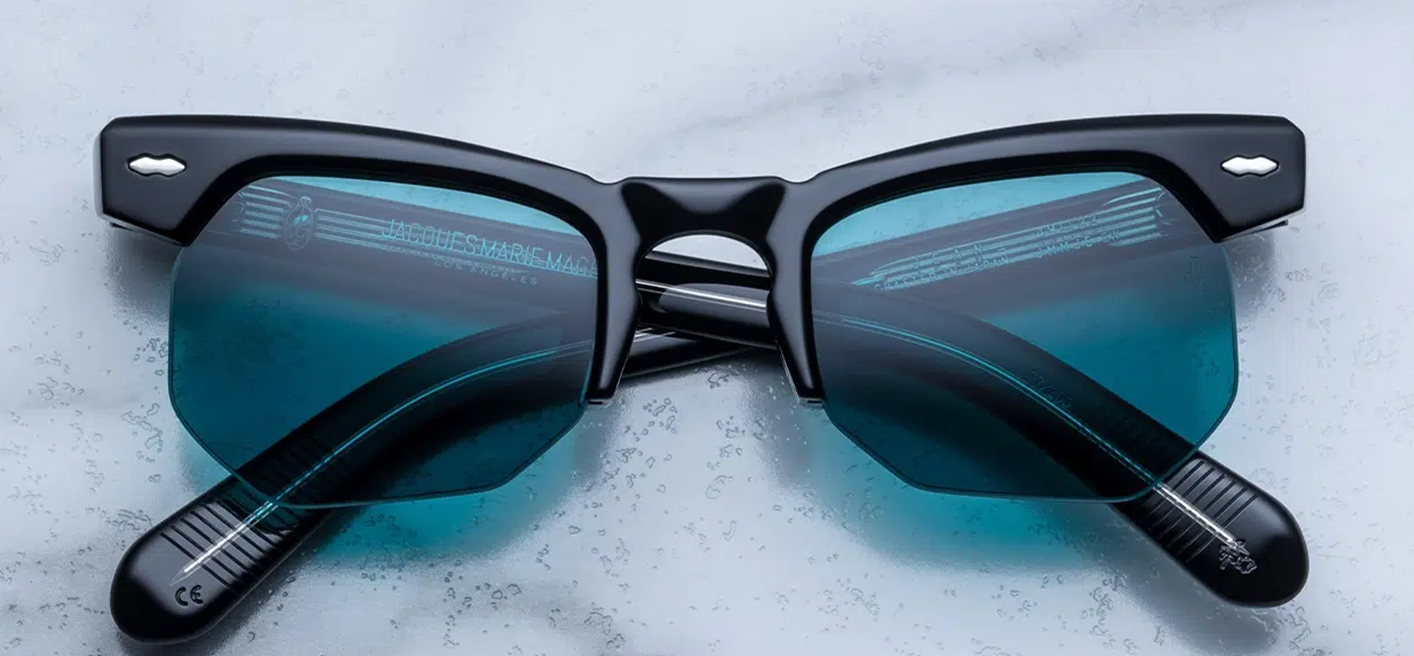 Semi‑rimless ’40s-inspired Jean frame in polished grey‑titan acetate, with a bold brow-line, angular lenses, and silver double-arrowhead front pin