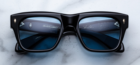 
Jacques Marie Mage Cash Eclipse 2 sunglasses inspired by Johnny Cash’s 1965 El Paso eyewear. Crafted from black 10 mm cured cellulose acetate, the frame has a prominent brow line and sculptural temples. The lenses are azure tinted CR39 with backside anti reflective treatment and 100% UV protection. Inside one temple, a gold “Johnny Cash” foil signature and limited-edition serial number are stamped. Handcrafted in Japan, produced in a batch of 500 pieces
