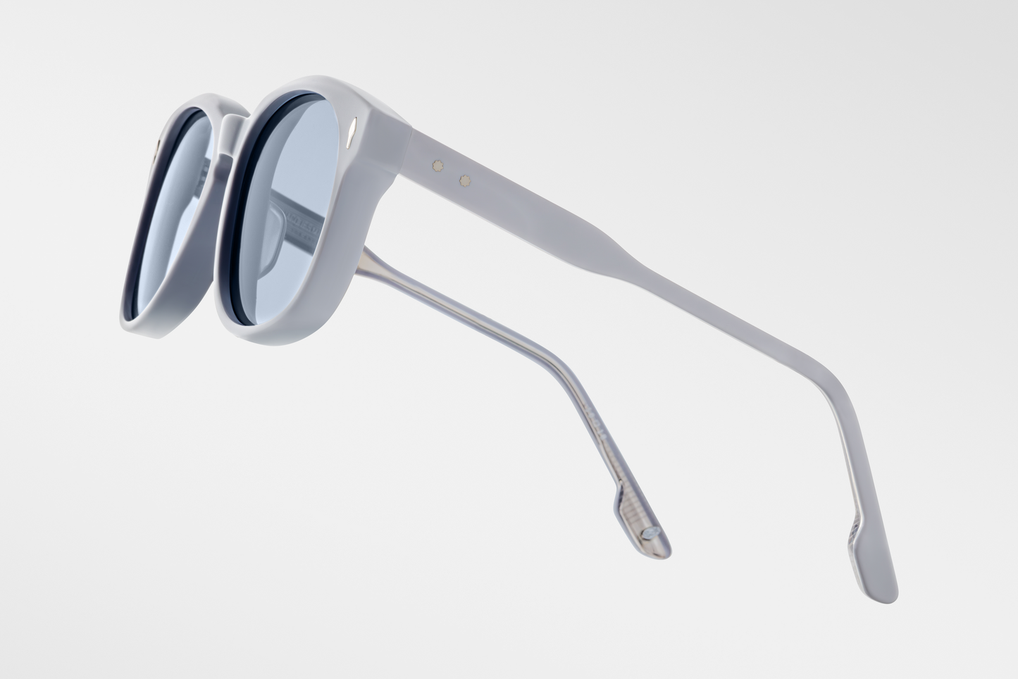 Left side of the Kay Sky Suede — matte blue acetate showing the silver hinge detail and the signature arrowhead pin near the front