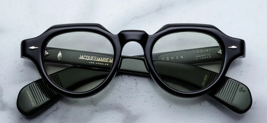 Front view of Jacques Marie Mage Kellerman eyeglasses in Cobra. The frames present a bold, sculptural, modified Panto-shape silhouette featuring a distinctively angular crown-panto top edge. Crafted from a substantial 10mm block of polished jet-black cured cellulose acetate, the face is decorated with JMM’s signature sterling silver arrowhead front pins at the upper outer corners. Available at WINK Optometrists.
