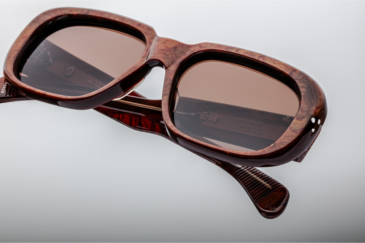 Close-up of the front of Kobo Burlwood sunglasses by Jacques Marie Mage, highlighting the unique frame design featuring  9 barrel hinge and brown lenses with antireflection coating