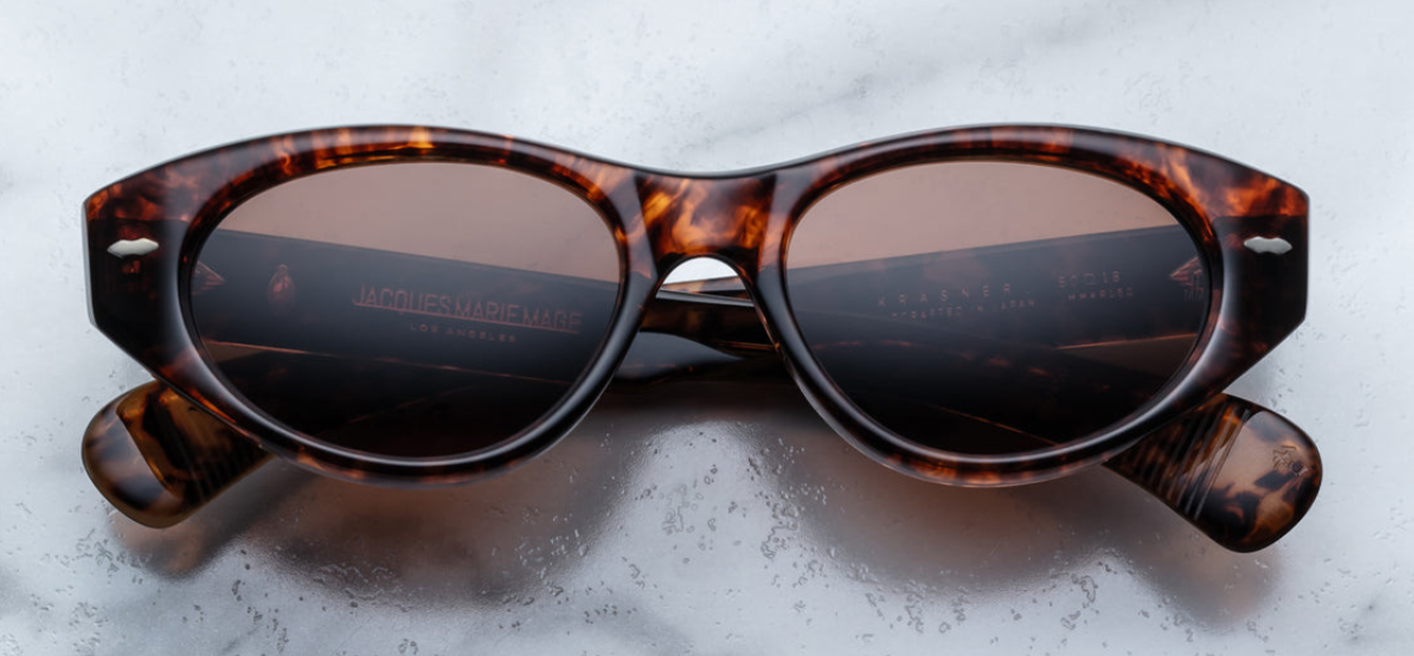 Front view of Jacques Marie Mage Krasner sunglasses in Samoa, featuring a soft, mid-size cat-eye frame with an elegant oval lens shape. Crafted from 10mm havana cured cellulose acetate, the frame showcases silver signature double-arrowhead front pins and an exposed silver lever wirecore, reflecting the frame's artisanal craftsmanship