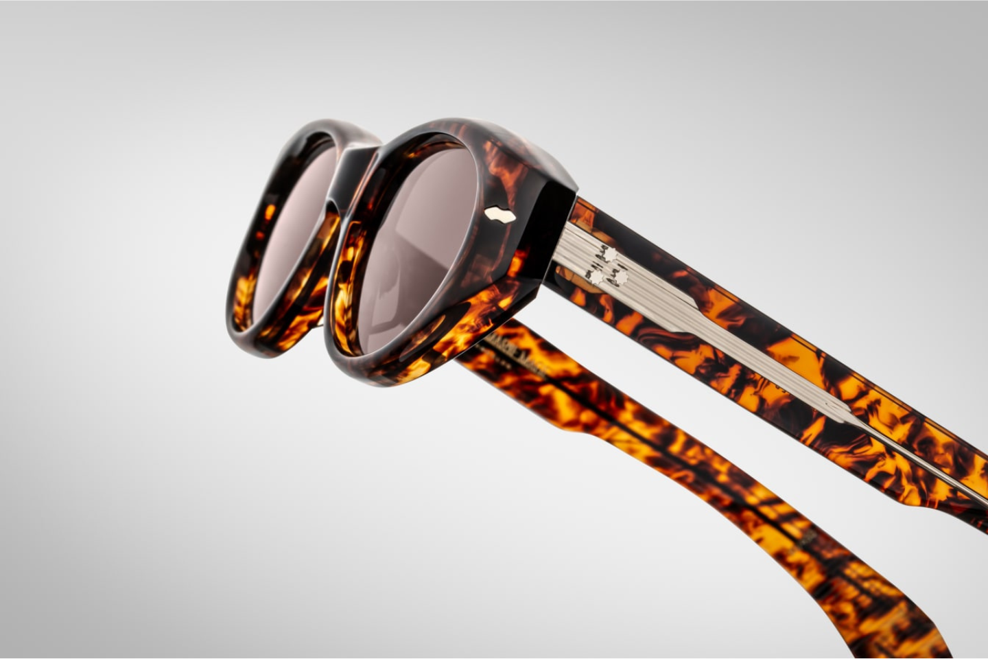Side profile of Jacques Marie Mage Krasner sunglasses in Samoa, highlighting the custom double-laminated acetate temples with precious metal hardware. The temples feature a silver tension-secured custom 7-barrel hinge, emphasizing the frame's luxurious design.