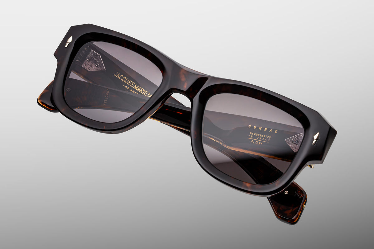 Top-down view of Jacques Marie Mage Conrad Beau sunglasses. Highlights the substantial 10mm thickness and sharp bevels of the Havana acetate frame top. The perspective outlines the straight alignment of the clear beige temples and braided gold wirecores extending back