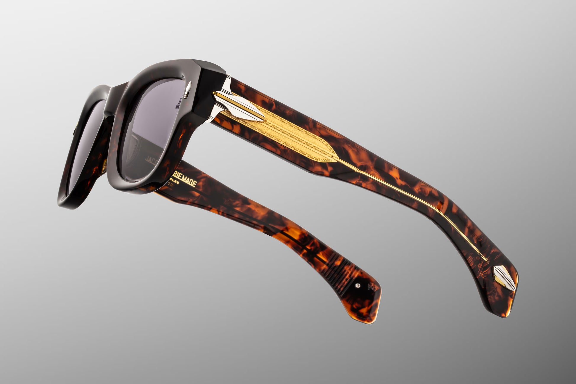 Side profile of JMM Conrad Beau sunglasses highlighting the ornate temples. The double-laminated temples feature a clear beige acetate exterior that leaves a custom-braided dark gold wirecore fully visible. Detailed silver palladium-plated arrowhead ornaments sit at the hinge assembly