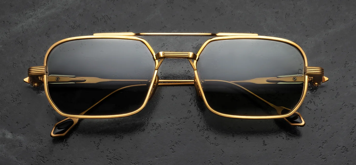 Front view of Jacques Marie Mage Deaver Maxi sunglasses. Features a medium 1990s-inspired rectangular dark gold titanium frame with a sleek top bar and double bridge. The eye rims feature fine silver palladium Chimayo textile engravings and hold solid grey Harbor mineral glass lenses