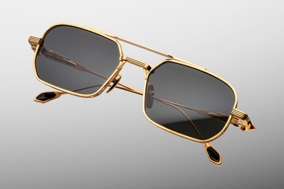 Top-down view of Jacques Marie Mage Deaver Maxi sunglasses, detailing the sleek profile of the dark gold navigator frame. Highlights the thickness of the top bridge, the alignment of the silver palladium accents, and the straight temple arms extending backward