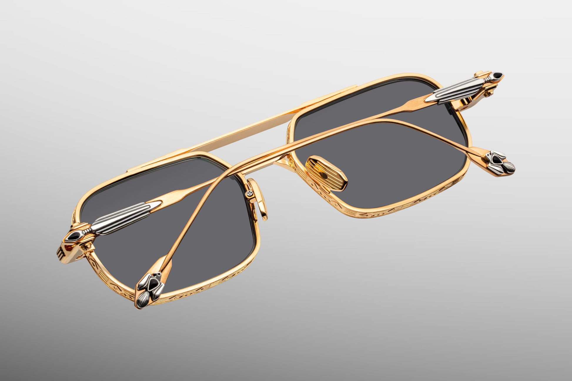 Rear view looking into the interior construction of Jacques Marie Mage Deaver Maxi frames. Shows the anti-reflective backside treatment of the grey lenses, dark gold titanium nose pads engraved with the JMM logo, and the internal design of the custom monoblock hinges