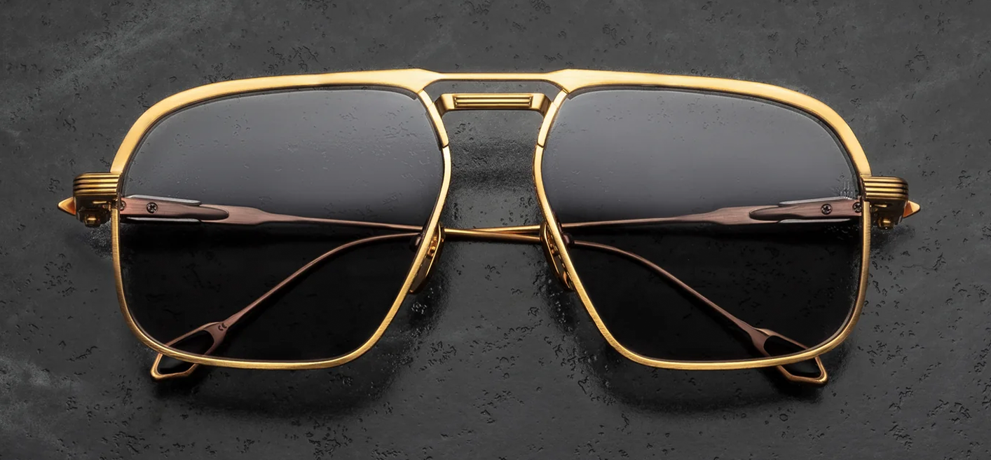 Front view of Jacques Marie Mage Labarge Maxi sunglasses. Features a large 1970s-inspired dark gold titanium navigator frame with a thick monoblock top bar and silver palladium accents. The eye rims display fine Chimayo textile engravings and hold solid grey armorlite lenses