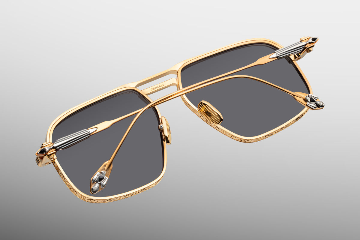 Rear view looking at the interior construction of Jacques Marie Mage Labarge Maxi sunglasses. Shows the anti-reflective backside treatment of the grey lenses, dark gold titanium nose pads engraved with the JMM logo, and the internal mechanics of the custom monoblock hinges