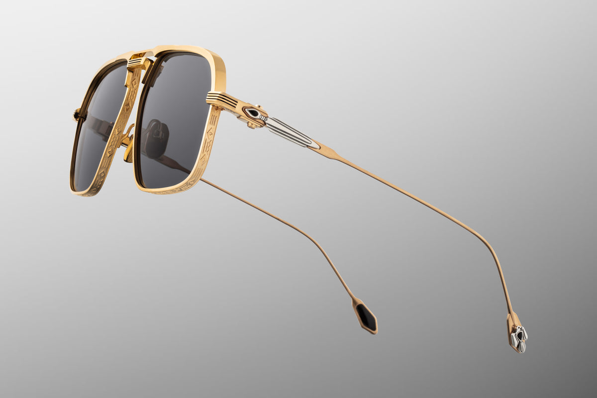  Side profile of JMM Labarge Maxi sunglasses highlighting the detailed temples. The dark gold beta-titanium arms feature sculptural sterling silver arrowhead motifs inlaid with hand-shaped black onyx gemstones. The frames are secured with custom silver monoblock hinges.