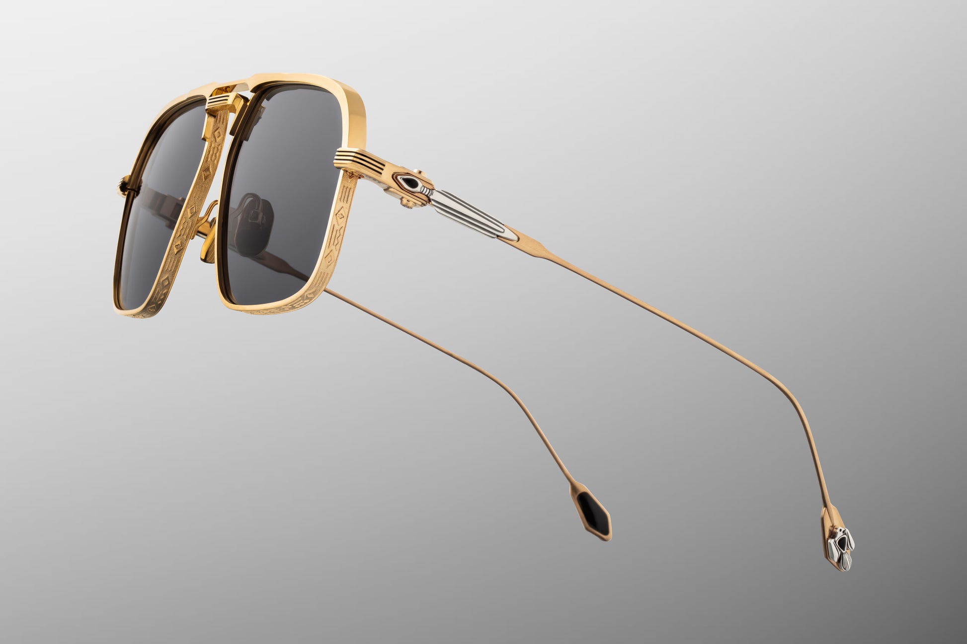  Side profile of JMM Labarge Maxi sunglasses highlighting the detailed temples. The dark gold beta-titanium arms feature sculptural sterling silver arrowhead motifs inlaid with hand-shaped black onyx gemstones. The frames are secured with custom silver monoblock hinges.
