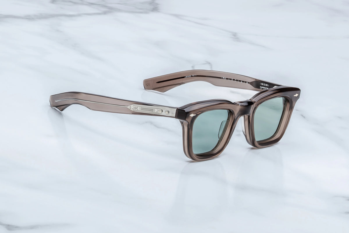 Profile view of the Jacques Marie Mage Leclair Dusty Jade sunglasses. The thick, sculpted temple arm extends straight back, transitioning from the translucent taupe acetate frame front into a double-laminated temple structure. An intricately engraved metallic "Snaketail" wirecore is visible through the clear acetate of the arm, leading toward the curved ear piece.