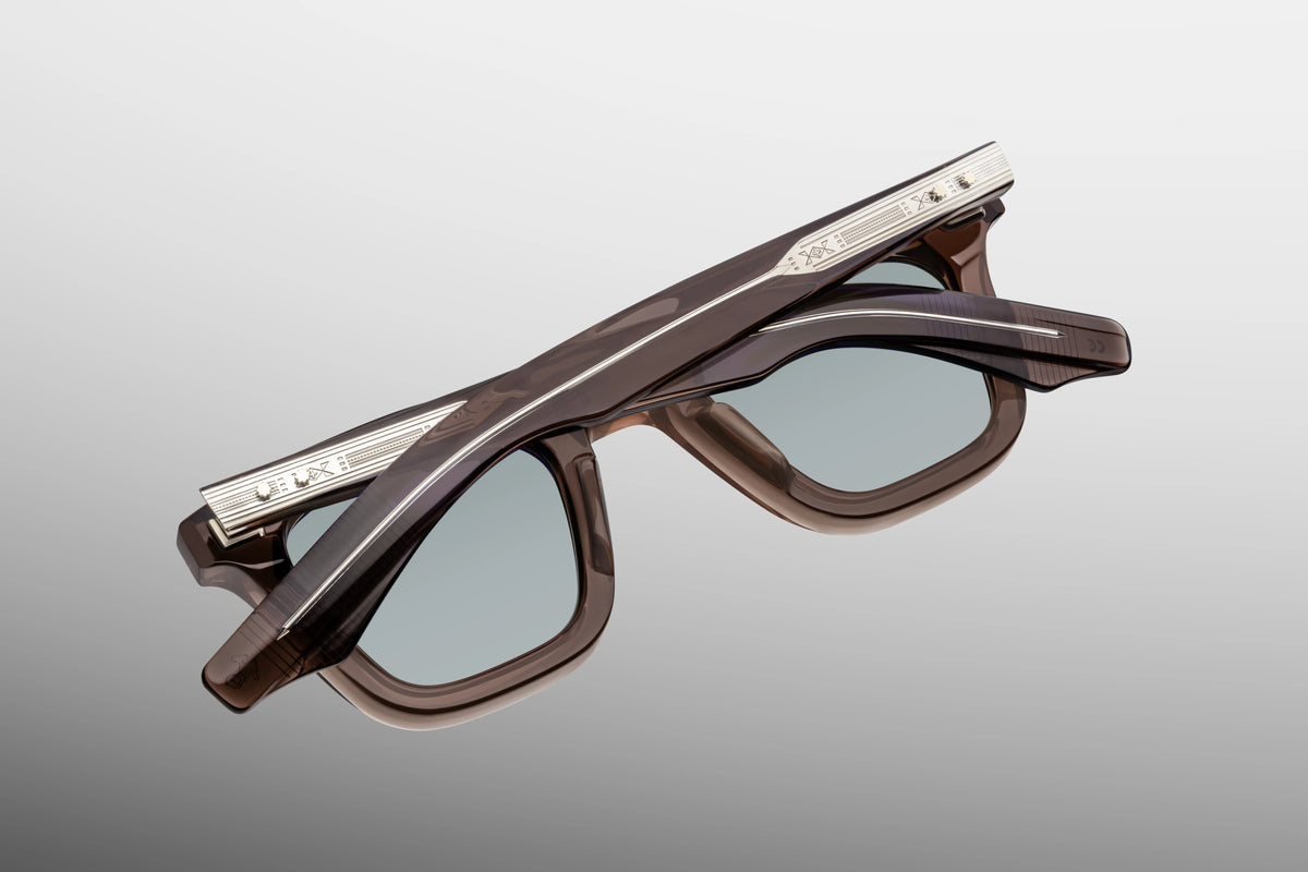 Detailed close-up view from behind the hinge of the JMM Leclair sunglasses. This perspective reveals the heavy-duty, tension-secured silver 5-barrel hairline hinge anchoring the temple arm to the frame chassis. Gold or silver foil-stamped branding text and the limited-edition batch number are visible along the interior temple surface against the smooth acetate.
