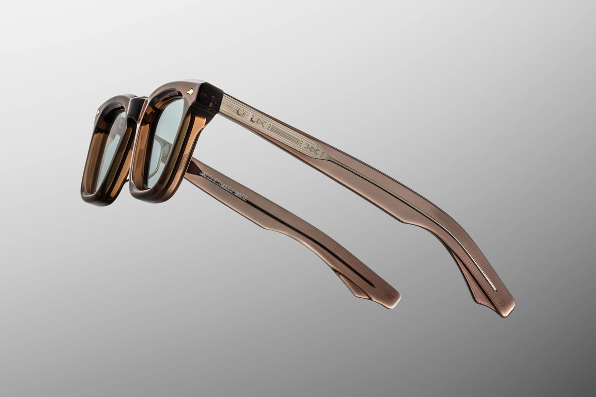 Focused close-up of the temple arms of the Leclair Dusty Jade glasses. The image emphasizes the custom, exposed "Snaketail" wirecore running through the center of the translucent arm. The metal is meticulously detailed with fine, custom hairline engravings that shimmer through the structured taupe acetate ove