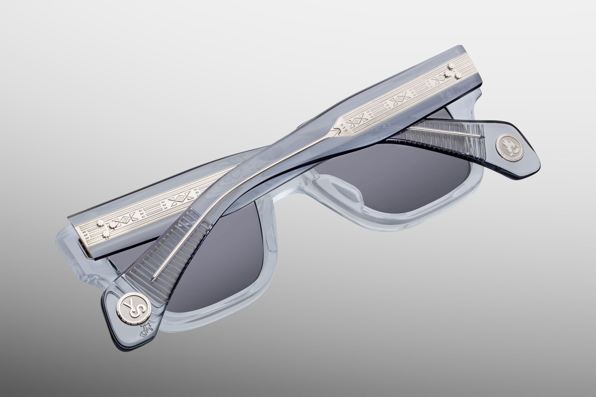 Detailed view of 'Howling Wolf' and 'YS' medallions at the temple tips of Lupine Storm glasses, emphasizing artisanal craftsmanship.