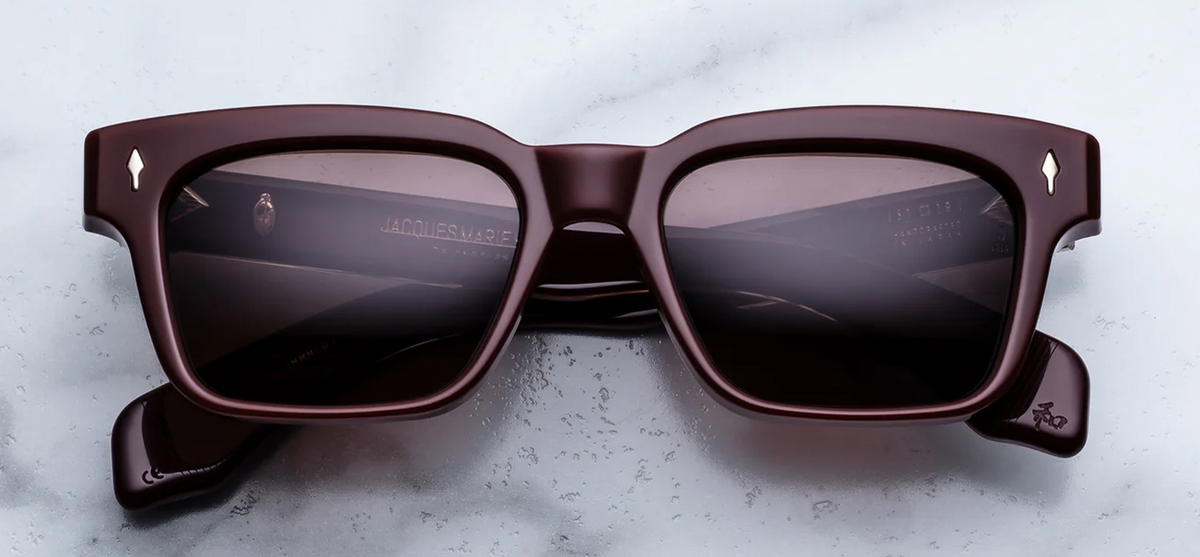 Front view of Jacques Marie Mage Molino Bordeaux Empire sunglasses. Displays a bold, 1960s-inspired rectangular 10mm block acetate frame in a high-gloss, deep wine-red burgundy, fitted with solid deep brown lenses and sterling silver arrowhead pins. Wink Optometrists