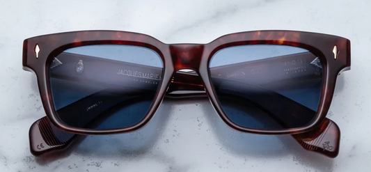 Front view of Jacques Marie Mage Molino 51 sunglasses in Breccia Havana tortoise shell acetate, showcasing a bold rectangular 1960s-inspired frame with Prussian Blue lenses and light gold arrowhead pins