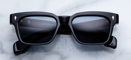 Front view of Jacques Marie Mage Molino Lacquer sunglasses. Features a 1960s-inspired, mid-sized rectangular 10mm block acetate frame in an ultra-deep ink blue that borders on black, fitted with solid smoky dark lenses and gleaming light-gold arrowhead pins. WINK OPTOMETRISTS
