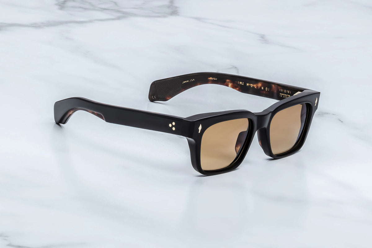 Three-quarter view of the Jacques Marie Mage Molino Noir 15 sunglasses. The angle highlights the heavy frame volume, hand-polished brow beveling, and dual-layered temples that reveal a silver filigree wire core beneath translucent clear inner acetate.