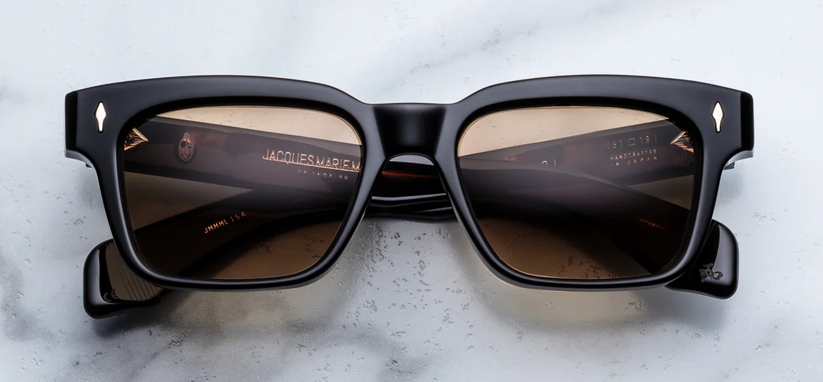 Front view of Jacques Marie Mage Molino Noir 15 sunglasses. Displays a bold, 1960s rectangular 10mm block acetate frame in a high-gloss, solid polished black, fitted with distinct brass gradient lenses and sterling silver arrowhead pins.
