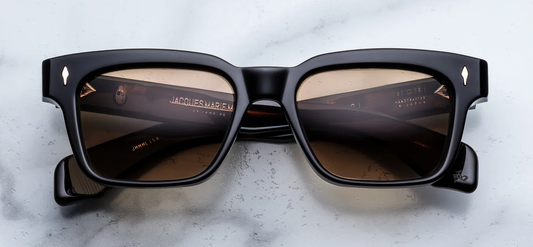Front view of Jacques Marie Mage Molino Noir 15 sunglasses. Displays a bold, 1960s rectangular 10mm block acetate frame in a high-gloss, solid polished black, fitted with distinct brass gradient lenses and sterling silver arrowhead pins.