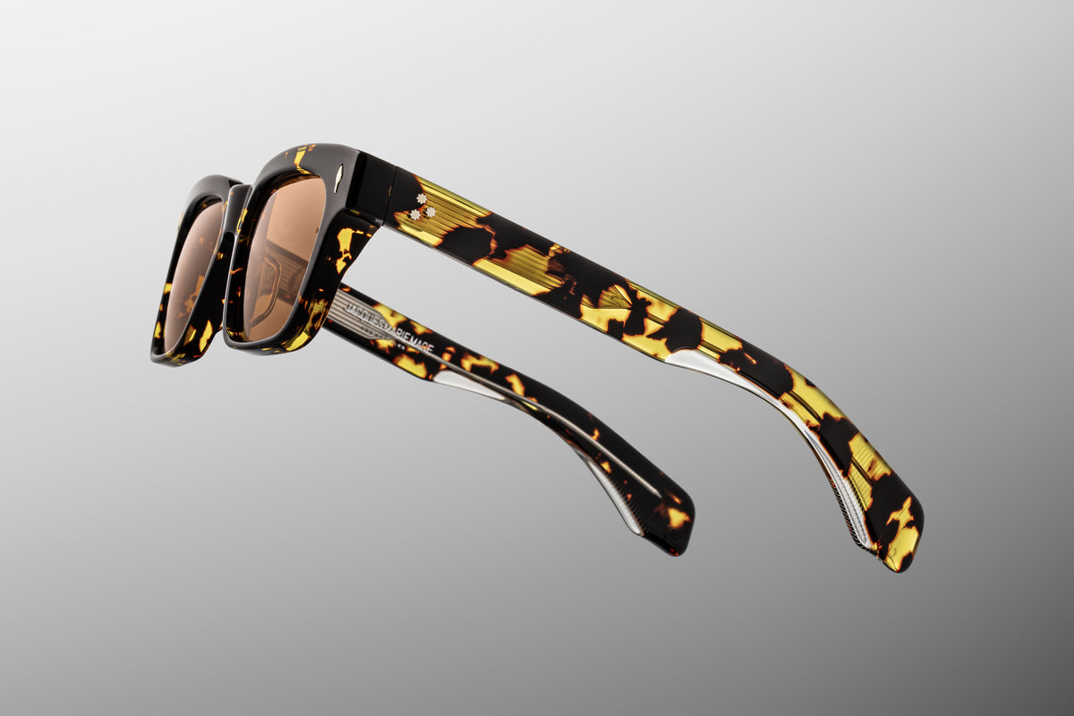 Macro shot of the inner temple arm on Jacques Marie Mage Molino Tokyo sunglasses. The crystal-clear interior laminate layer provides a window to the exposed silver palladium wire core engraved with intricate hairline filigree.
