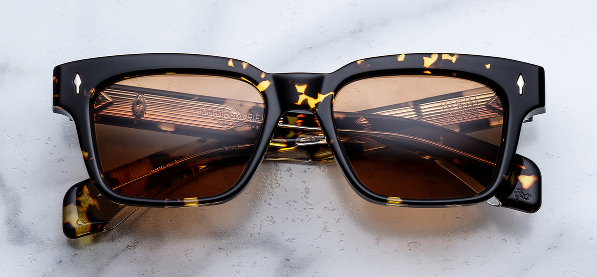 Front view of Jacques Marie Mage Molino Tokyo sunglasses. Displays a bold, 1960s-inspired rectangular 10mm block acetate frame in a warm, dark-based polished Havana tortoiseshell pattern, fitted with high-contrast, solid orange-tinted lenses and sterling silver arrowhead pins. ink Optometrists