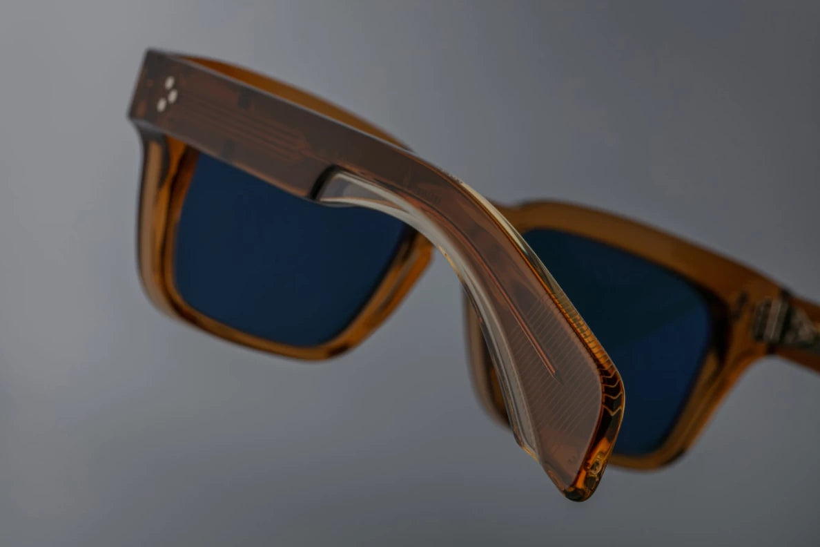 Side view of the JMM Molino 51 sunglasses temple arm, showcasing the glossy Whiskey-colored outer temple, the internal custom hairline-engraved wirecore, and a sterling silver spur-shaped rivet.