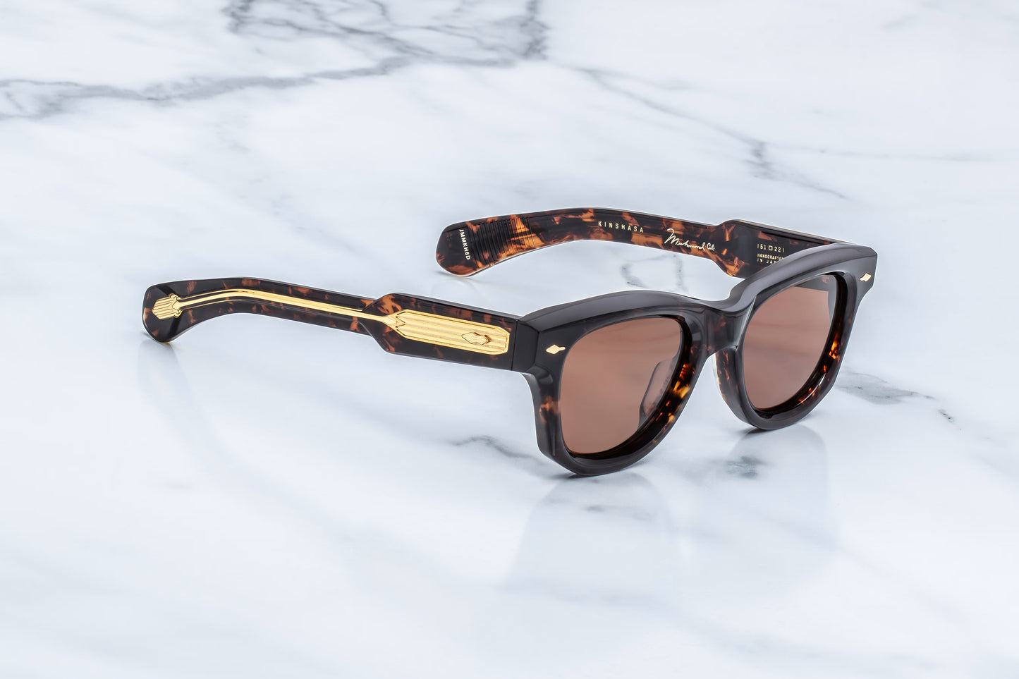 Three-quarter studio shot of the JMM Kinshasa in Agar, showcasing the thick 10mm beveled acetate frame, sienna lenses, and the sculptural transition from the front frame to the temples