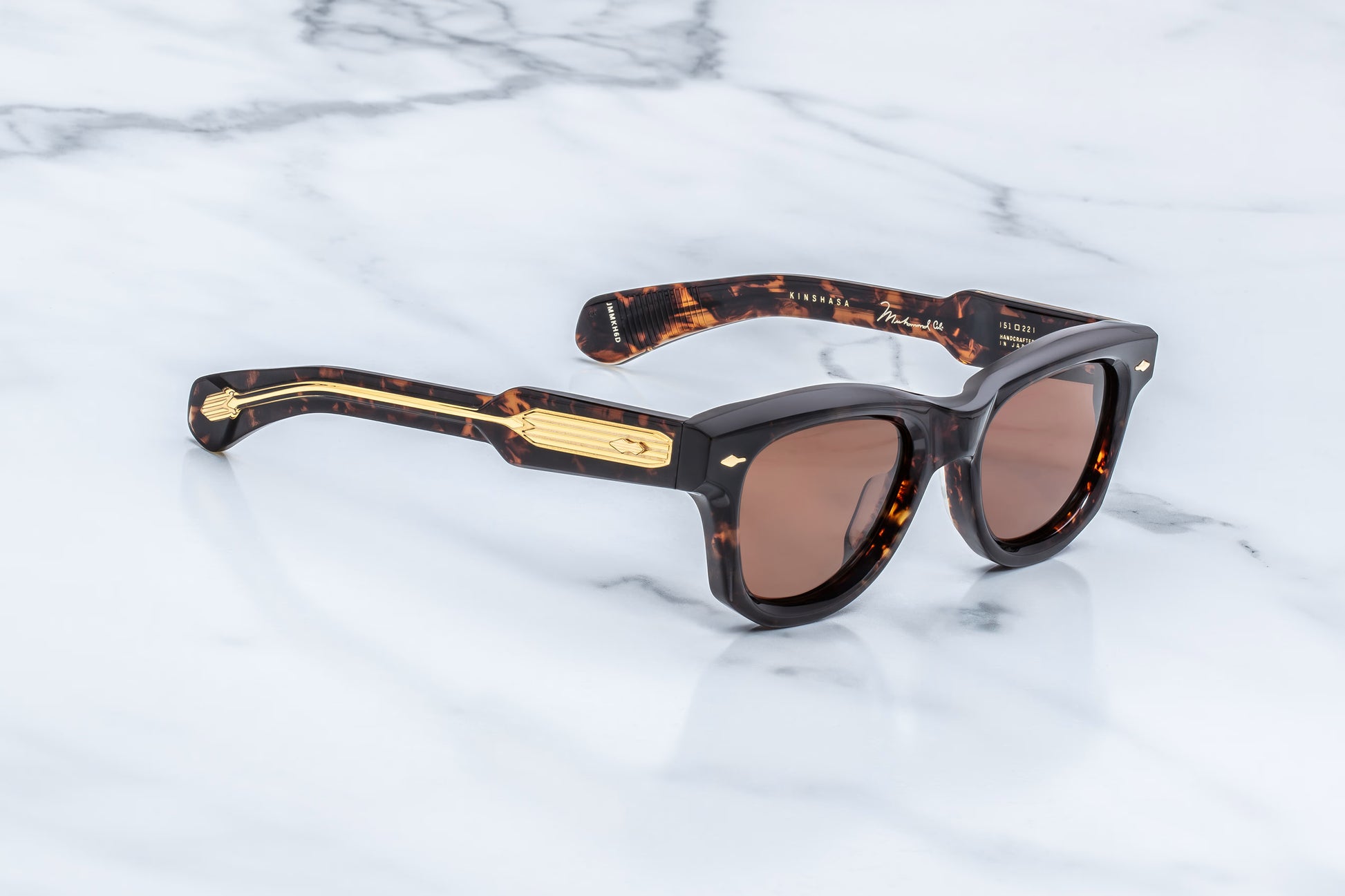 Three-quarter studio shot of the JMM Kinshasa in Agar, showcasing the thick 10mm beveled acetate frame, sienna lenses, and the sculptural transition from the front frame to the temples