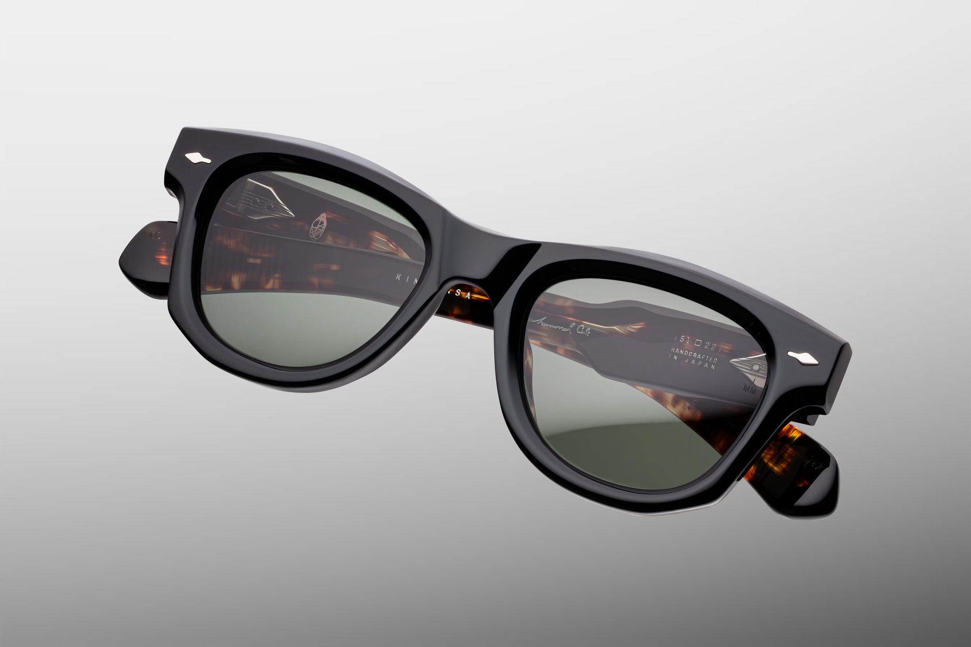 Top-down view of the JMM Kinshasa Noir sunglasses, revealing the frame’s curved geometry, the substantial 10mm thick black acetate brow line, and the heavy-duty 7-barrel block hinges