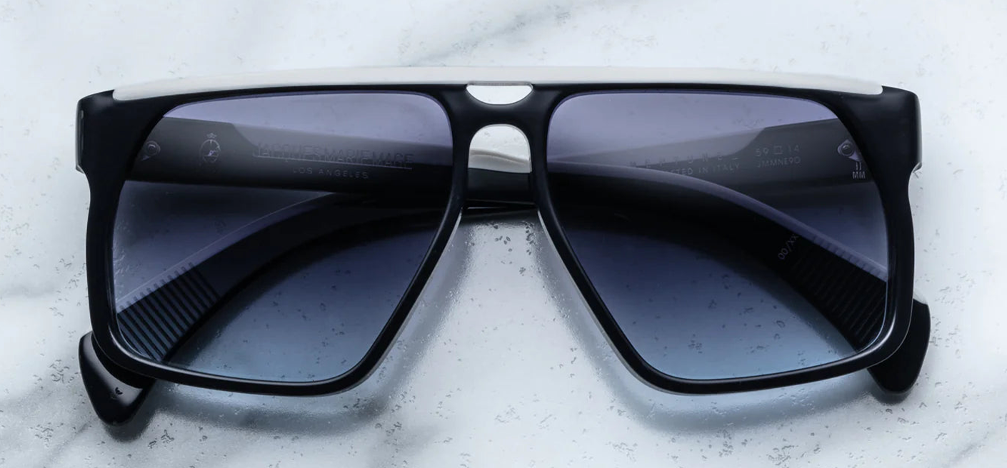 An up-close view of the Jacques Marie Mage Neptune sunglasses lenses, showcasing the oxford blue gradient CR39 lenses with backside anti-reflective coating. The lenses are 6-base, providing full UV protection. The frame is constructed from 8mm cured cellulose acetate, ensuring durability and a premium feel.