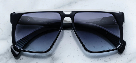 An up-close view of the Jacques Marie Mage Neptune sunglasses lenses, showcasing the oxford blue gradient CR39 lenses with backside anti-reflective coating. The lenses are 6-base, providing full UV protection. The frame is constructed from 8mm cured cellulose acetate, ensuring durability and a premium feel.