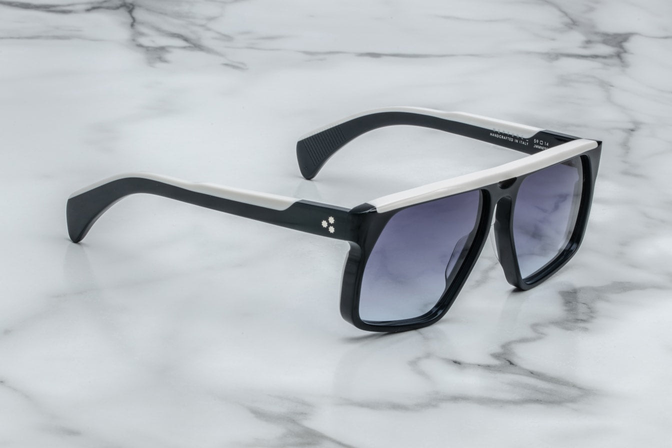 A profile view of the Neptune sunglasses, highlighting the sculpted acetate temples that taper towards the ear. The temples are double-laminated with a contrasting light gold wirecore, adding a touch of elegance. The frame's bold lines and oversized design give it a distinct '80s-inspired look