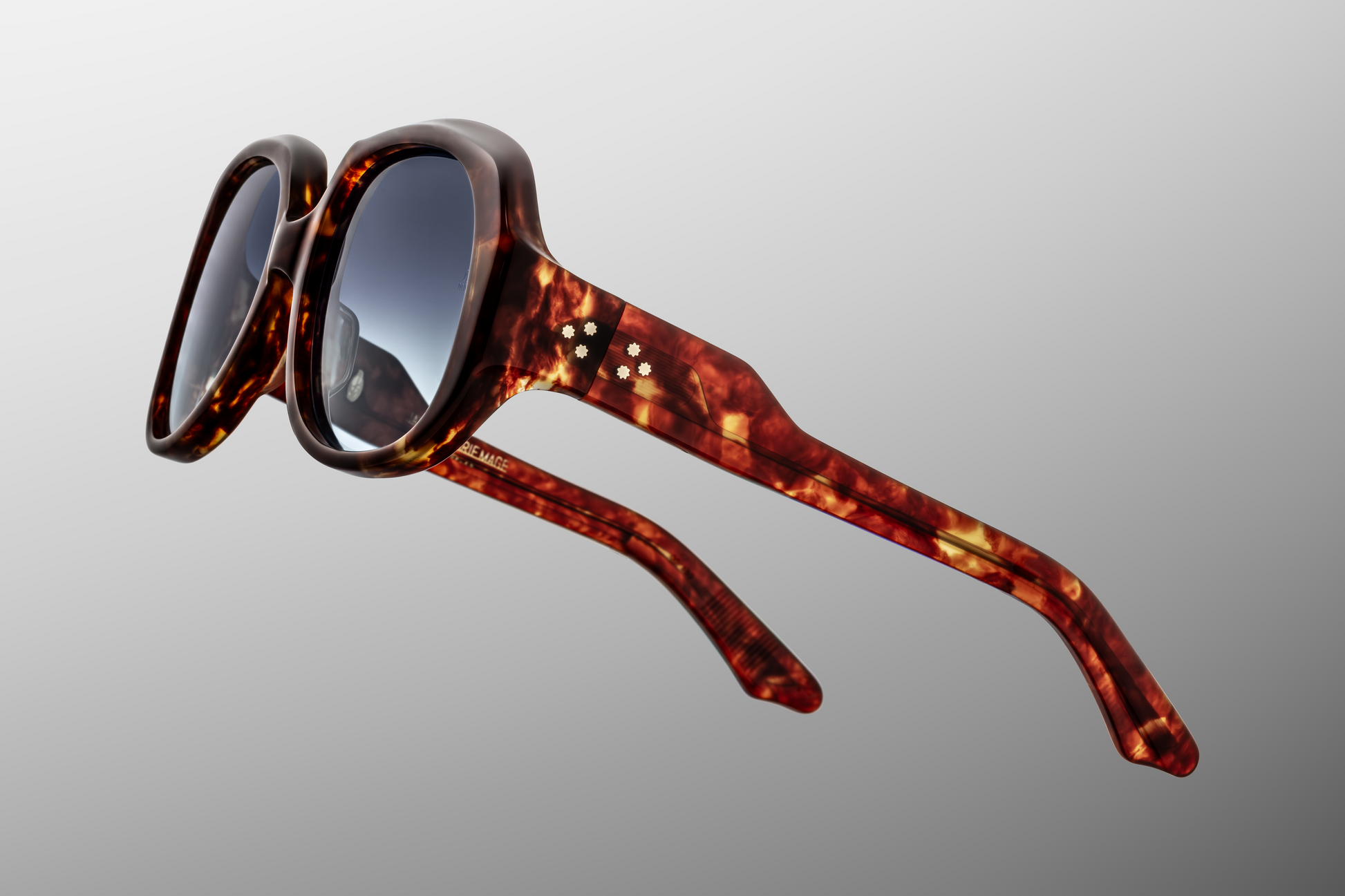 Close-up of the Ocean Child Breccia hinge — custom 7-barrel hinge plated in light gold, secured with spur-shaped rivets, built into warm breccia acetate