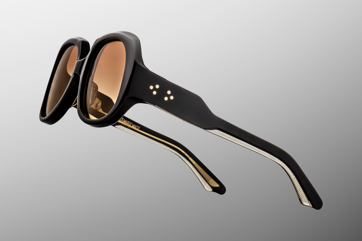 Close-up of the Ocean Child Beluga hinge — custom 7‑barrel hinge plated in 18k dark gold, secured with spur-shaped rivets in deep beluga acetate